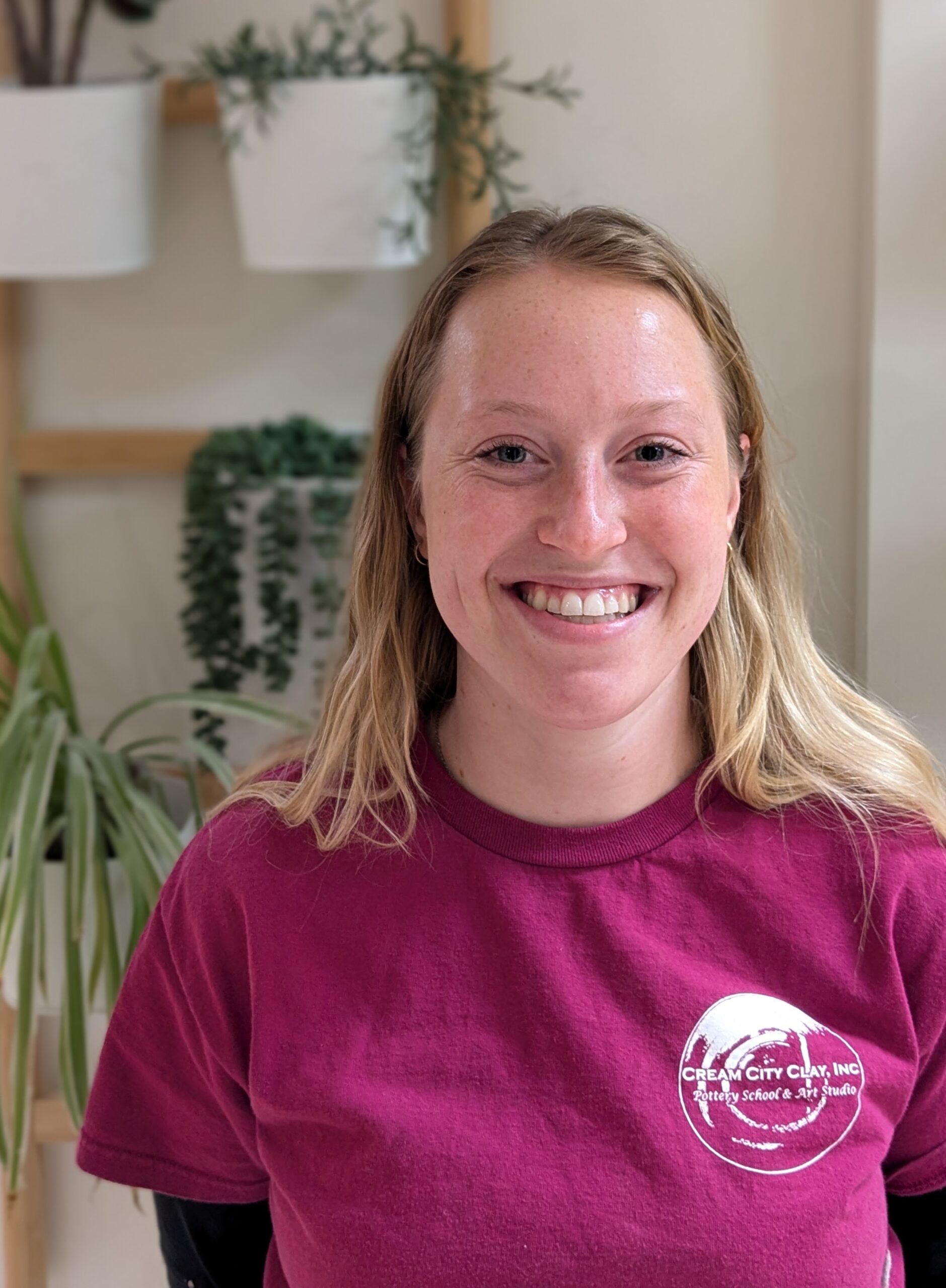 Smiling woman with blond hair blue eyes and pink Cream City Clay shirt