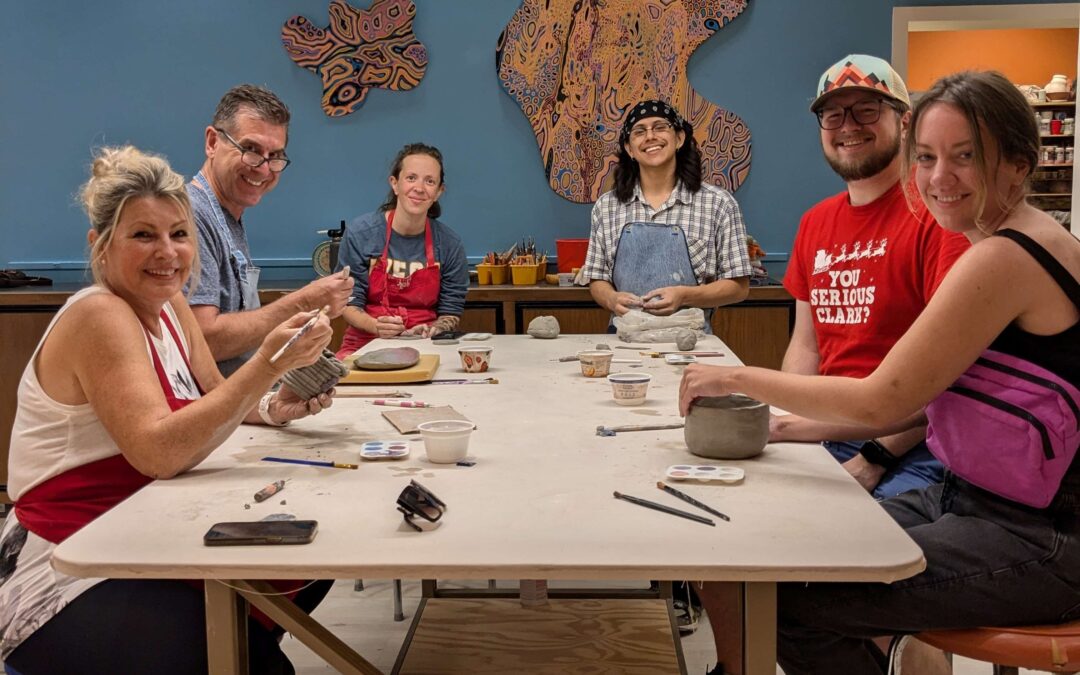 Group class working at a table making hand build clay projects